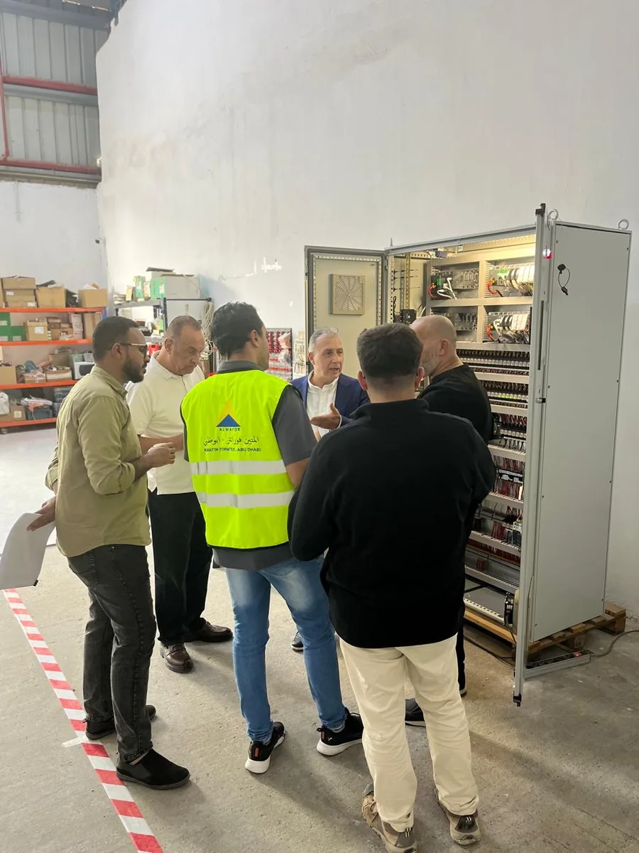 Almafor engineers and a client walking a wired control panel at the Mussafah workshop