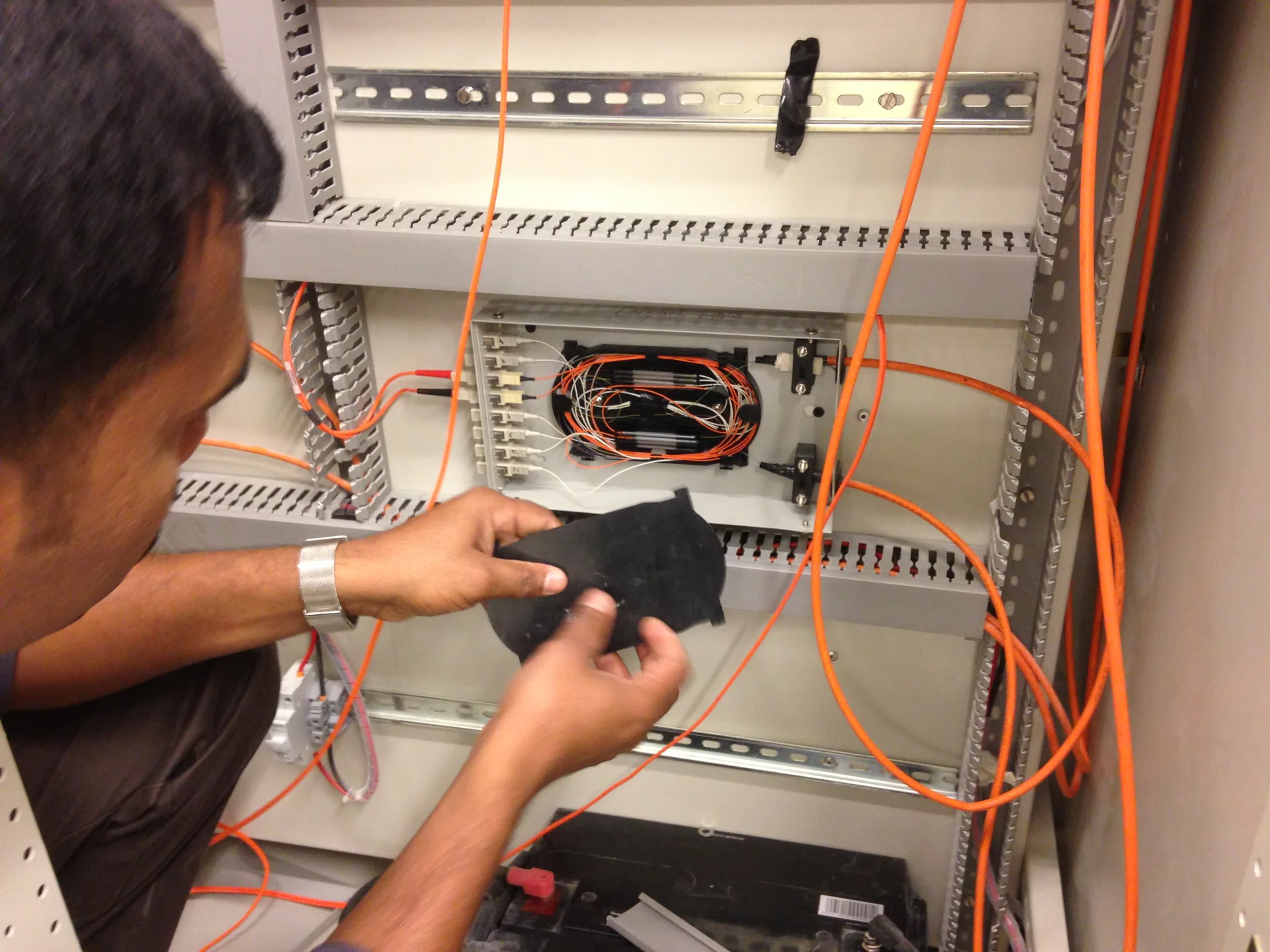 Engineer working on a fibre optic splice tray inside a communications cabinet